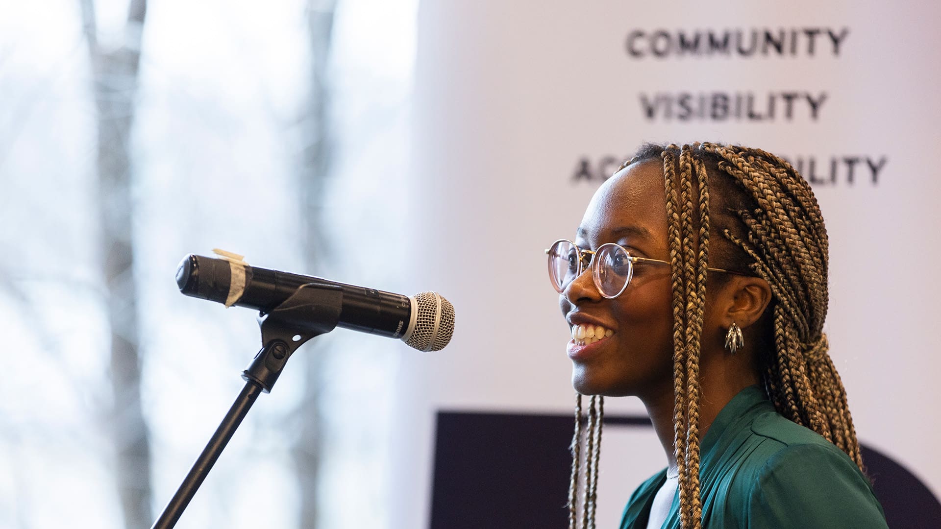 Speaker standing in front of a microphone at a Black on the Shelf event.