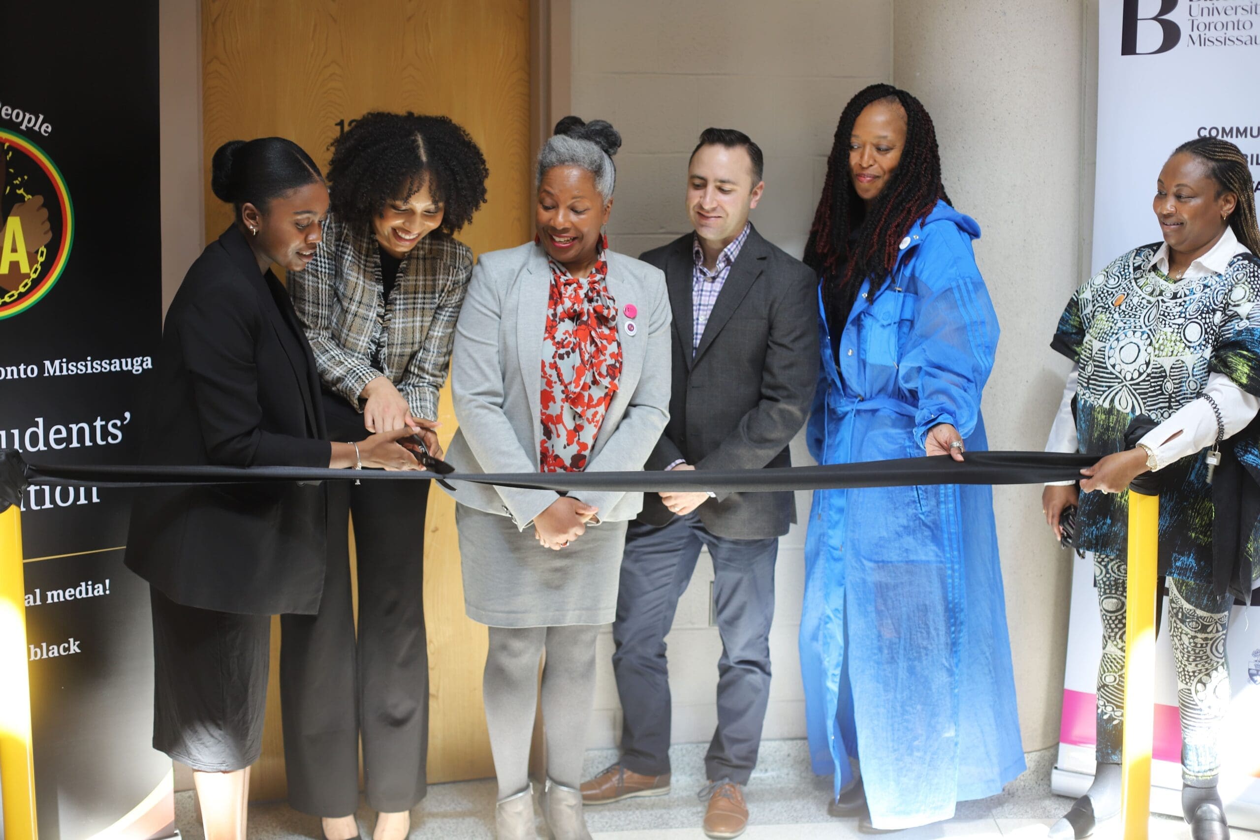 A group of Staff, faculty and students standing before the cutting of a black ribbon at the launch of the Black Student Space.