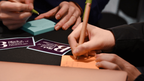 Closeup photo of Black At UTM event attendees writing suggestions on sticky notes