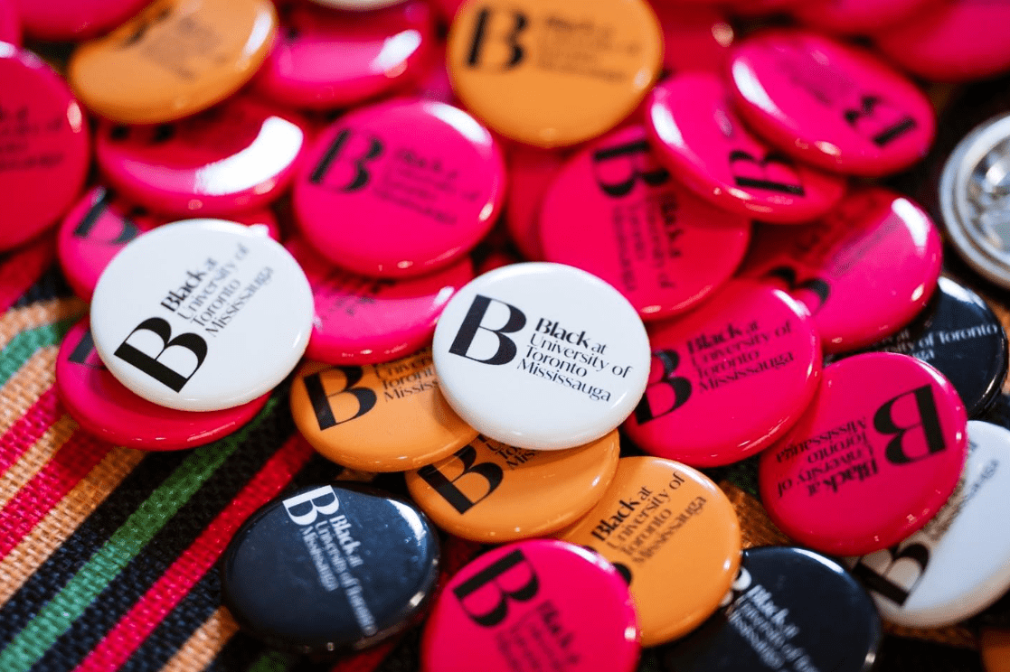 Black at UTM Close up of white, pink and orange Black at UTM buttons.